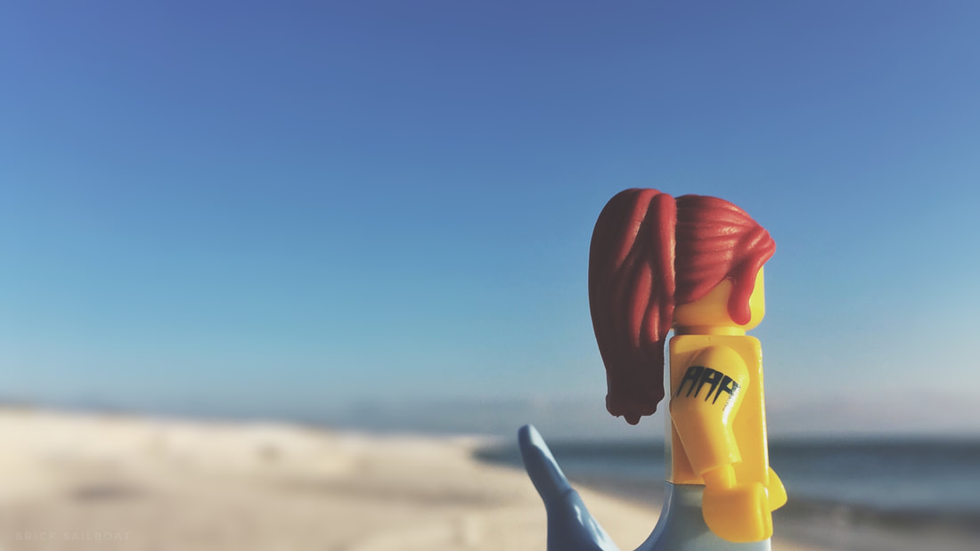 A LEGO mermaid on the beach staring at the ocean